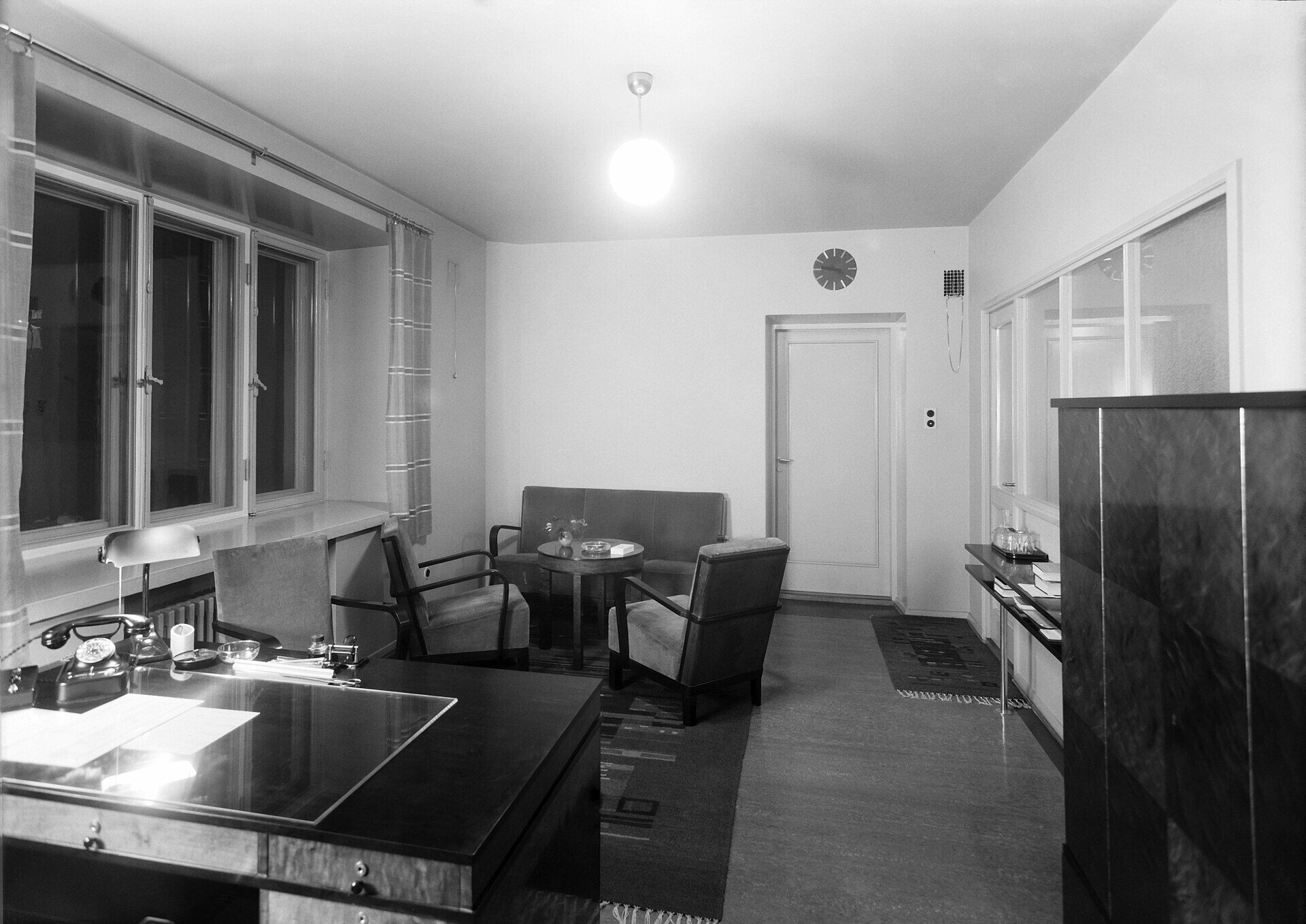 Ein leeres Büro der 1930er-Jahre mit Schreibtisch, Ledersesseln und Deckenlampe